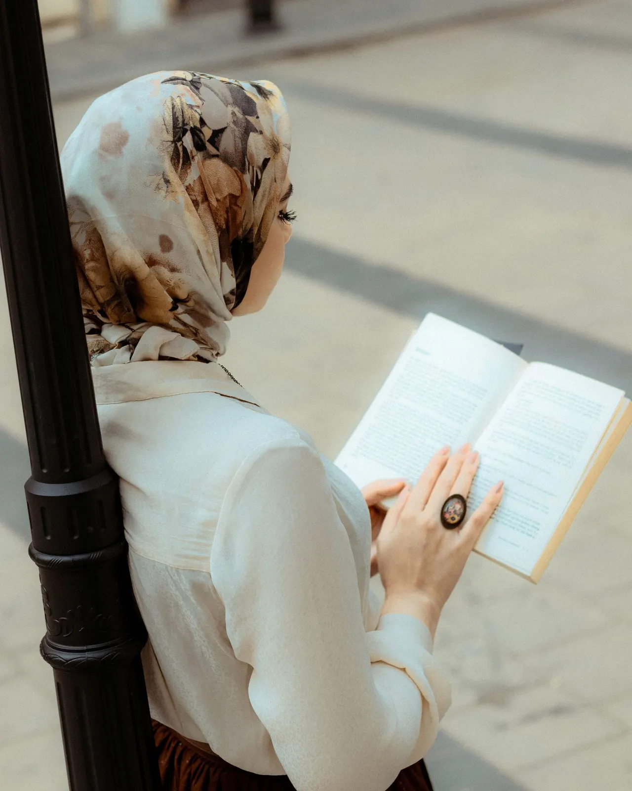 Reading in a floral printed headscarf on a sunny street